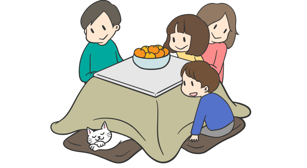 Family of four sits around a low table with a bowl of oranges on the table; a white cat naps beneath the blanket nearby.