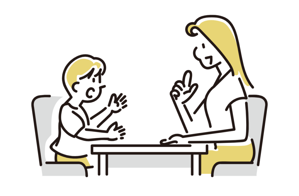 Child and adult sitting at a table, gesturing as they talk to each other.