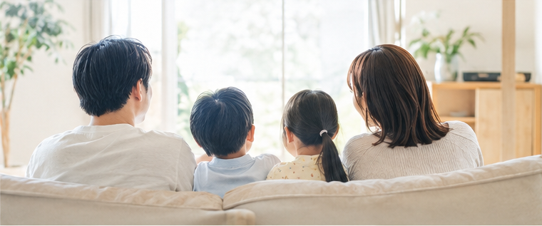 明るいリビングでソファに座り、家族でくつろぐ様子